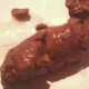 A woman takes a shit on the floor as seen from close up.